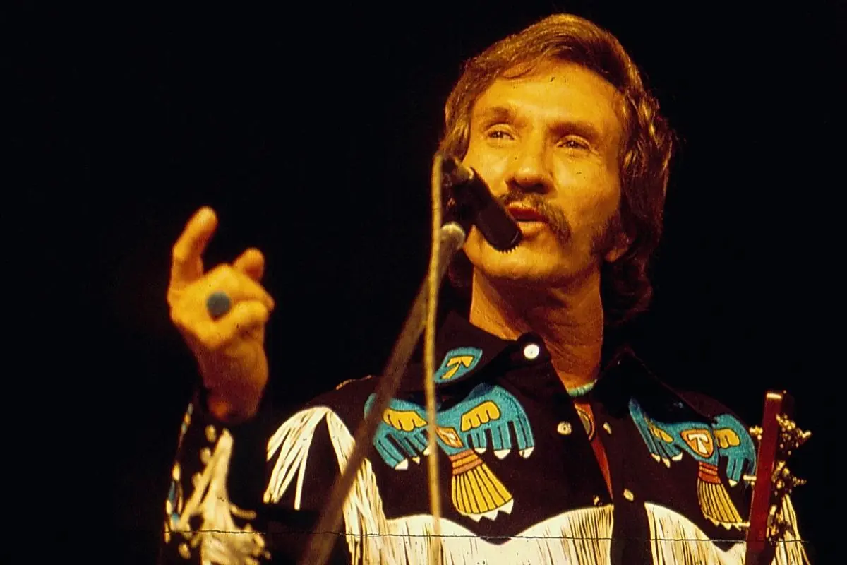 Marty Robbins sings into a microphone during a live performance.