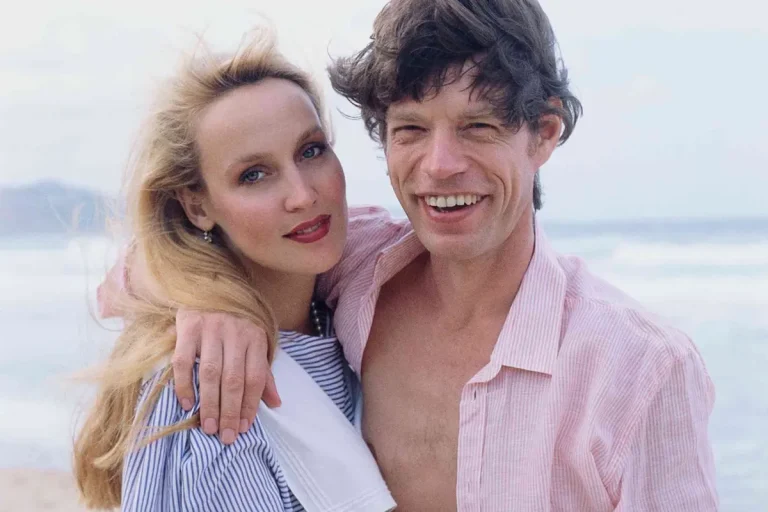 Mick Jagger & Jerry Hall: The Rockstar Romance That Wouldn’t Behave Mick Jagger and Jerry Hall pose together at the beach, smiling casually with arms around each other, reflecting their high-profile celebrity relationship.