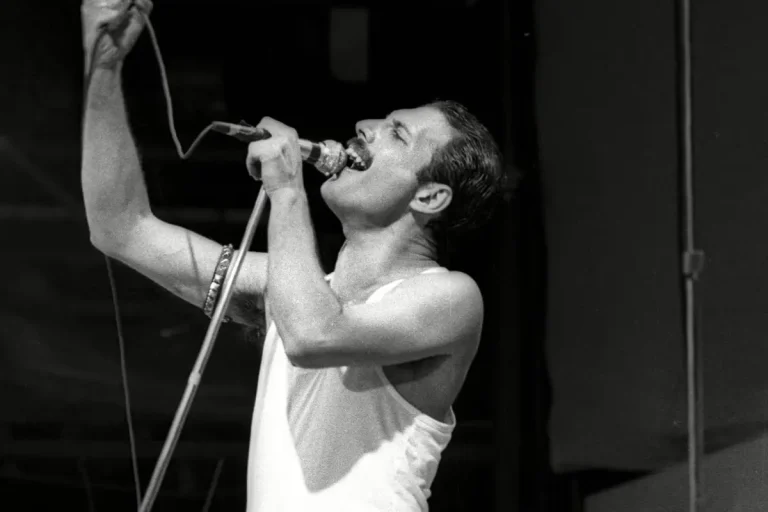 Freddie Mercury of Queen sings passionately into a microphone during a live performance, capturing his intense stage presence and vocal power.