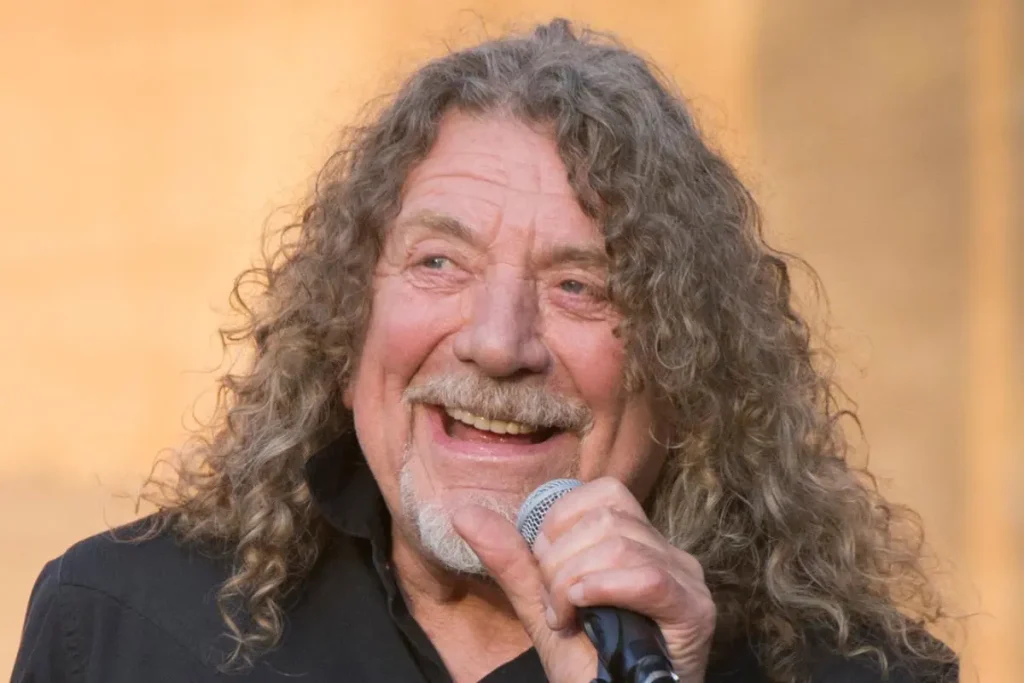 Robert Plant performing live, smiling while holding a microphone.