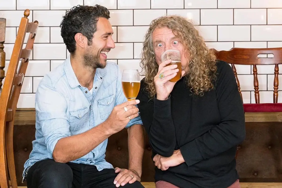 Robert Plant sharing a drink and laughing.