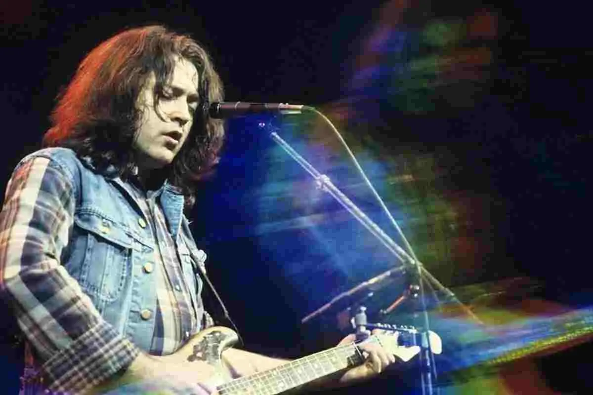 Rory Gallagher playing guitar and singing into a microphone