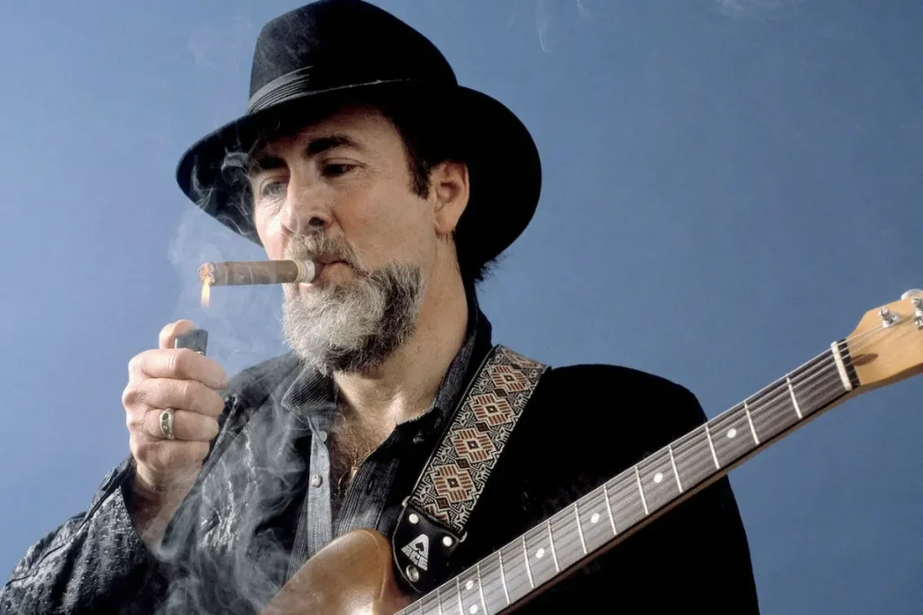 Roy Buchanan stands in quiet confidence, guitar in hand and cigar lit, embodying the understated mystique of a master who let his instrument speak louder than fame.