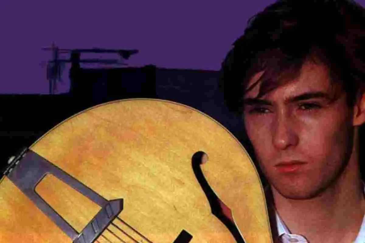 Scotty Moore holding a hollow-body guitar in an early color portrait.