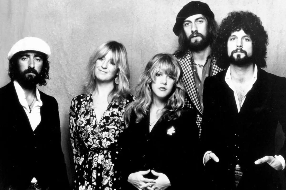 Fleetwood Mac standing shoulder to shoulder in coordinated vintage outfits, looking directly at the camera.