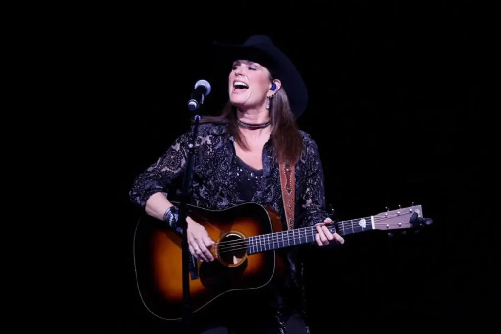 Terri Clark: Montreal-Born Opry Powerhouse Who Made ’90s Country Tell the Truth Terri Clark performing on stage, singing into a microphone while playing an acoustic guitar, dressed in black with a cowboy hat under concert lighting.