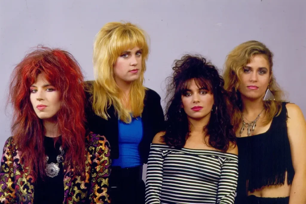 The Bangles stand together in an 1980s studio portrait, reflecting the band’s New Wave style and all-female presence in mainstream rock.