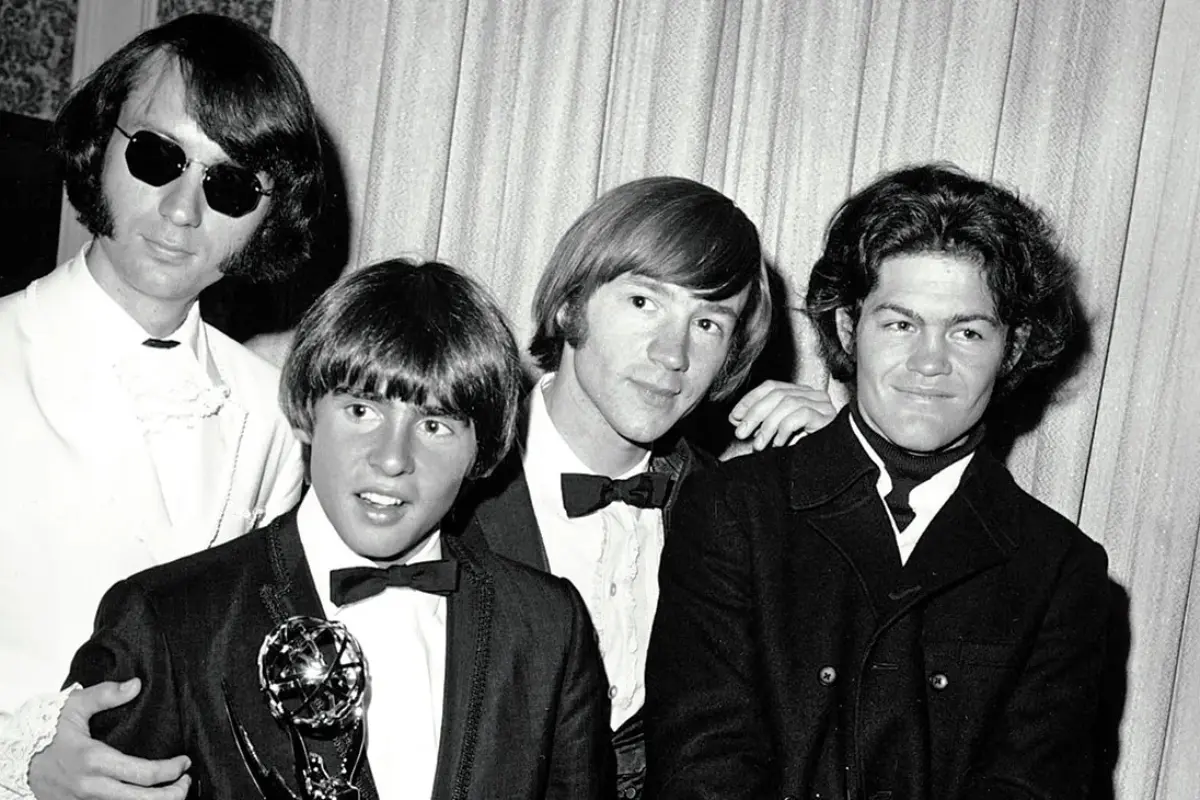 The Monkees stand together holding an award, reflecting their rapid rise to mainstream success during the height of 1960s pop music fame.