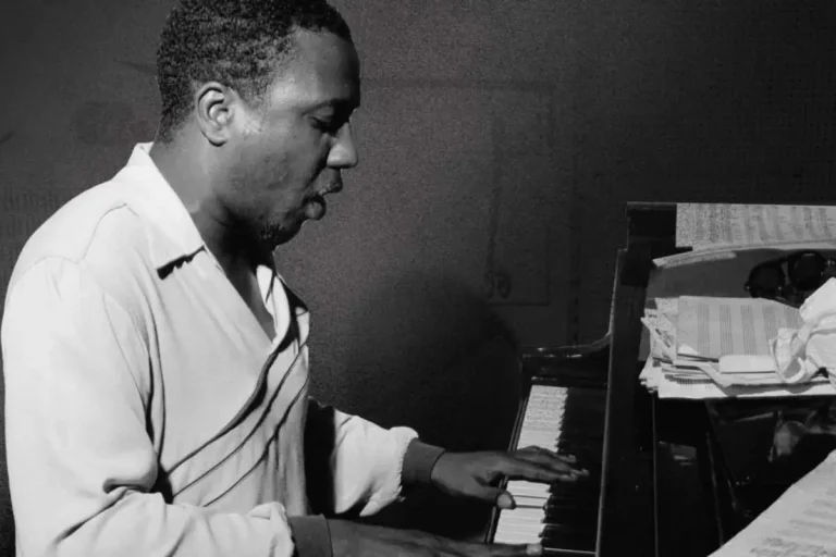 Thelonious Monk playing while reading sheet music, emphasizing discipline, creativity, and the craft of jazz composition.