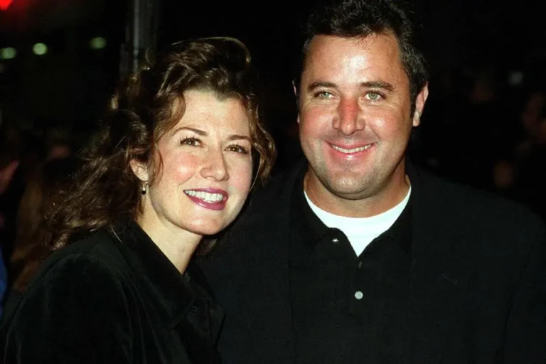 Amy Grant and Vince Gill posing together at a public event, both smiling toward the camera in a close-up photo.