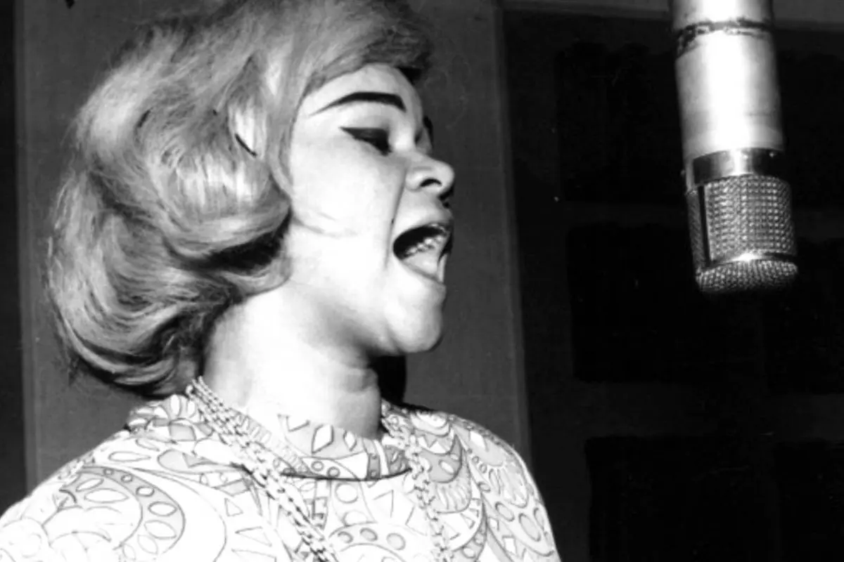 A young Etta James records vocals in a studio, capturing the early power and promise of her groundbreaking music career.