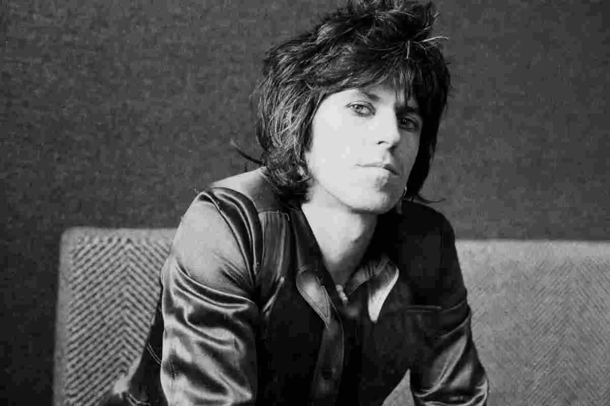 Keith Richards in a black-and-white portrait, seated indoors and looking directly at the camera.