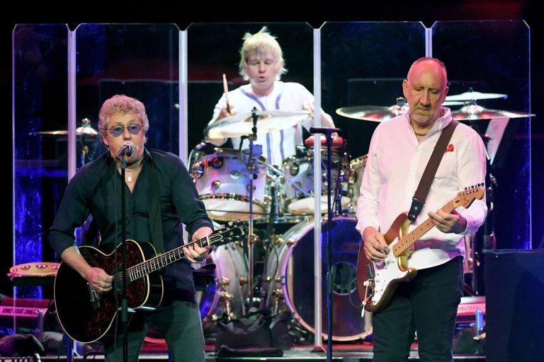 Roger Daltrey singing and playing an acoustic guitar, Zak Starkey behind the drum kit and Pete Townshend on electric guitar, performing onstage together as The Who