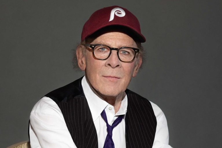 Art Garfunkel, 84, Says He Is ‘Thinking of Leaving the Country’ Over Donald Trump Art Garfunkel in a maroon Phillies cap, tortoiseshell glasses and a pinstriped waistcoat, seated against a grey studio backdrop