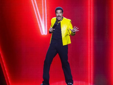 Lionel Richie Is Home From Intensive Care After the St. Louis Show He Finished Sitting Down Lionel Richie performing on stage in a yellow leather jacket against a red backdrop, holding a microphone