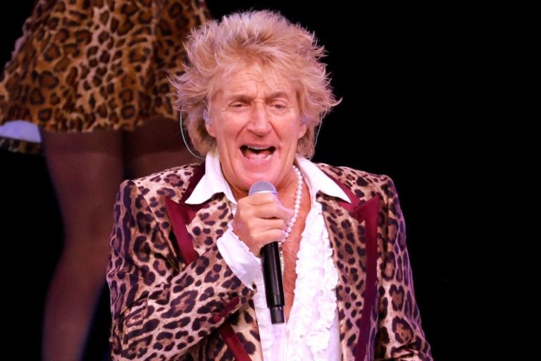 Rod Stewart Is Back in the Gym Three Times a Week at 81, Five Weeks After Heart Surgery Rod Stewart singing into a handheld microphone on stage, wearing a leopard-print jacket over a white ruffled shirt and a pearl necklace