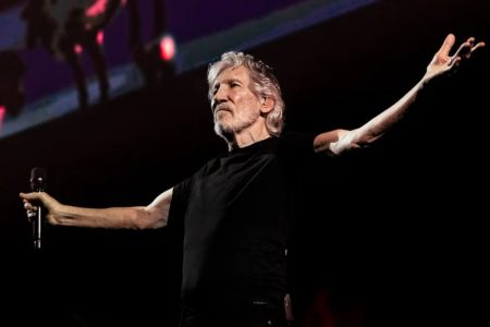 Roger Waters Calls Ed Sheeran a “Little P***k” as Every Support Act Quits the Loop Tour Roger Waters performing on stage in a black T-shirt, arms outstretched, holding a microphone