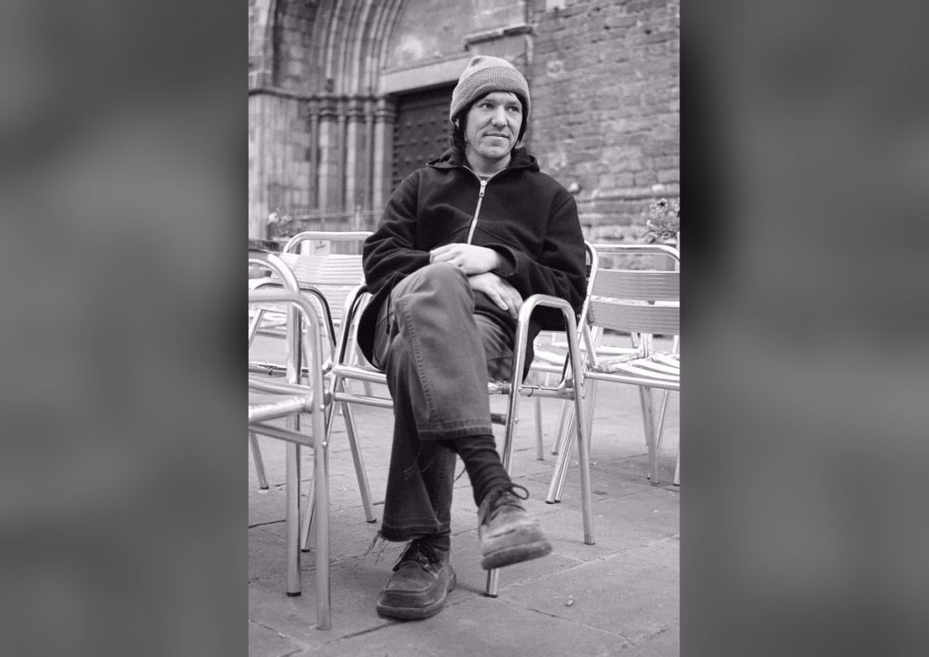 Elliott Smith archival portrait seated outside a cathedral