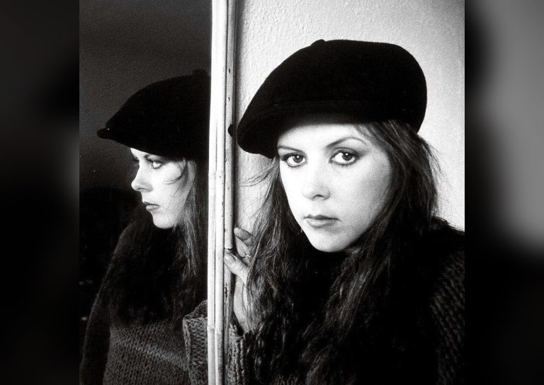 Kirsty MacColl in a black beret photographed beside her mirror reflection