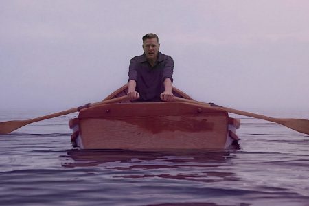 Bryan Adams Answers Trump’s ‘Lake America’ Order With New Song ‘Lake Ontario’ Bryan Adams rowing a wooden boat across calm water in the Lake Ontario music video